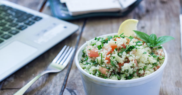 photo a bowle of salad on a wooden table with a laptop in the back round