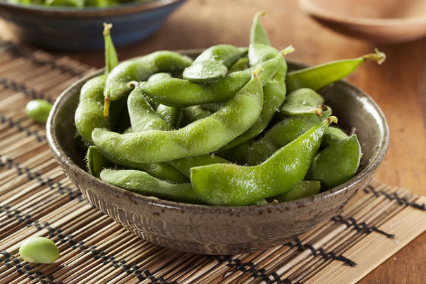 photo A rustic ceramic bowl filled with steamed edamame pods, served on a bamboo placemat on a wooden table
