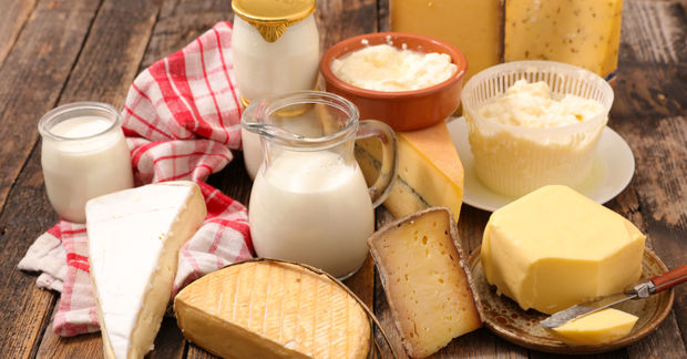 photo An assortment of dairy products including milk, butter, various cheeses, and cottage cheese on a rustic wooden table.