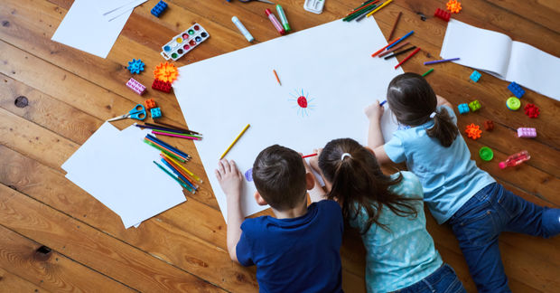 Three kids drawing and painting on a white paper