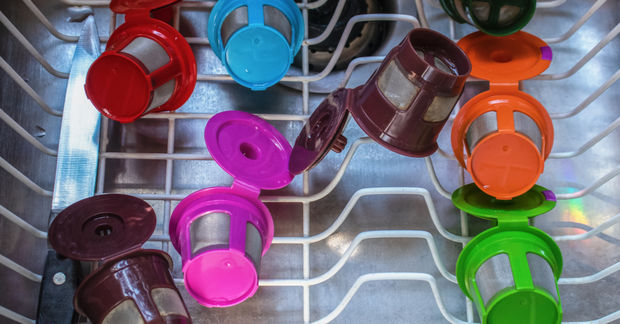 photo Colorful reusable coffee pods in various colors drying on a dishwasher rack, viewed from above.