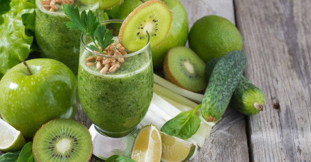 Green smoothie with kiwi garnish and fresh fruits.
