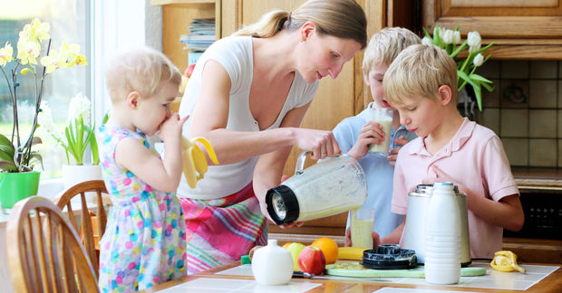 photo Mother preparing breakfast with two children in kitchen.