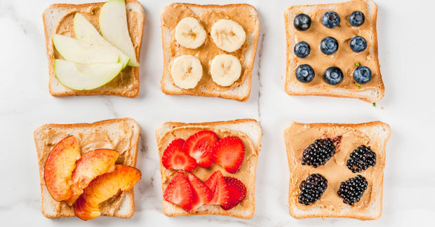 This Six slices of buttered whole wheat toast arranged in a grid, each topped with different fresh fruits: apple slices, banana, blueberries, peach slices, strawberries, and blackberries.